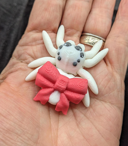 Our Beautiful Articulated Bow Spider Fidget Toy is  designed for both relaxation & decoration, is a versatile & delightful accessory. Its fully articulated body allows for posing, the bow adds a touch of charm that makes it perfect for the holidays.