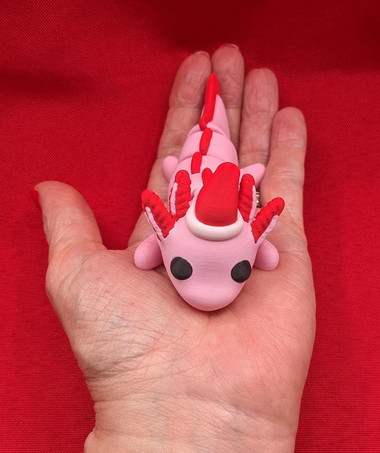 Celebrate the joy of the season with our Articulated Winter Christmas Axolotl Fidget Toy with a cute little Santa hat. This adorable and festive axolotl is perfect for spreading holiday cheer and providing endless fun.