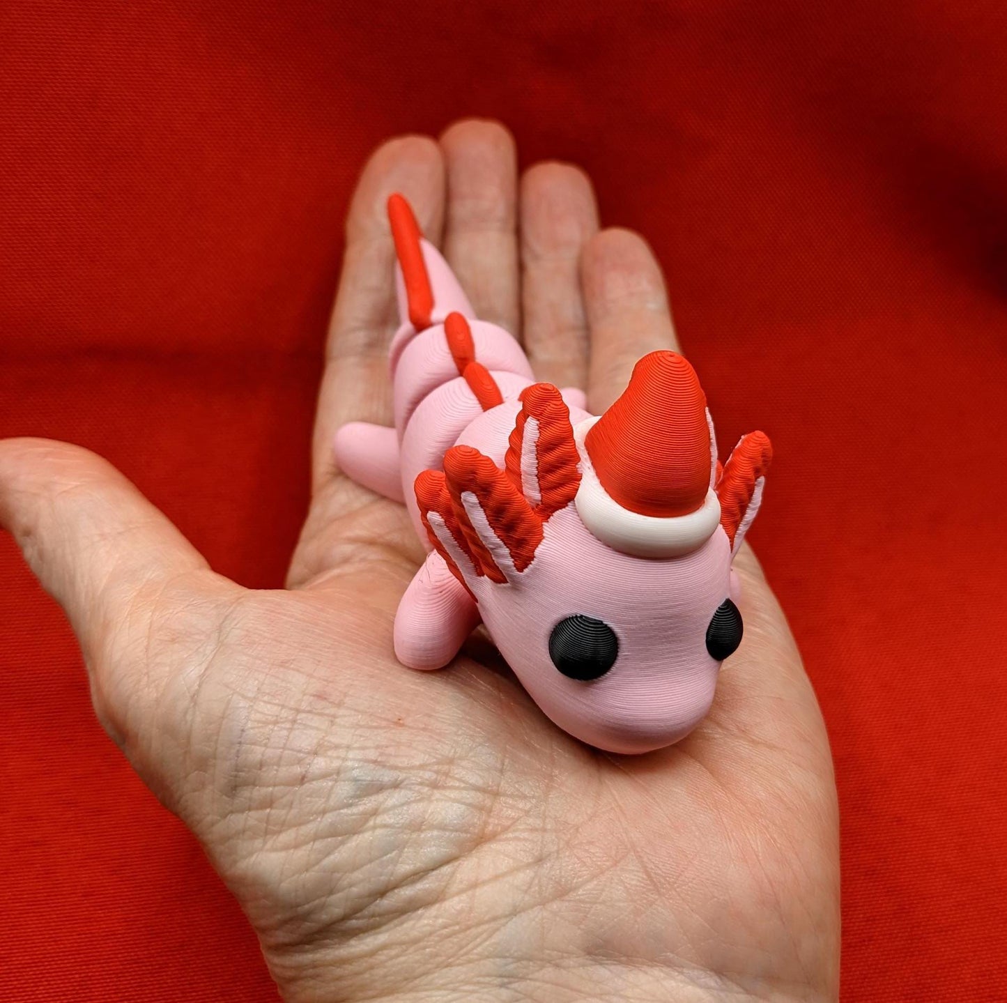 Celebrate the joy of the season with our Articulated Winter Christmas Axolotl Fidget Toy with a cute little Santa hat. This adorable and festive axolotl is perfect for spreading holiday cheer and providing endless fun.