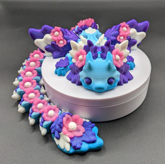 Unleash the magic of the our Beautiful Large Articulated 3D Printed Winged Kosha Axolotl Dragon! This stunning & unique creation combines the whimsical charm of an axolotl with the mythical beauty of a dragon, complete with sparkling wings & flowers.