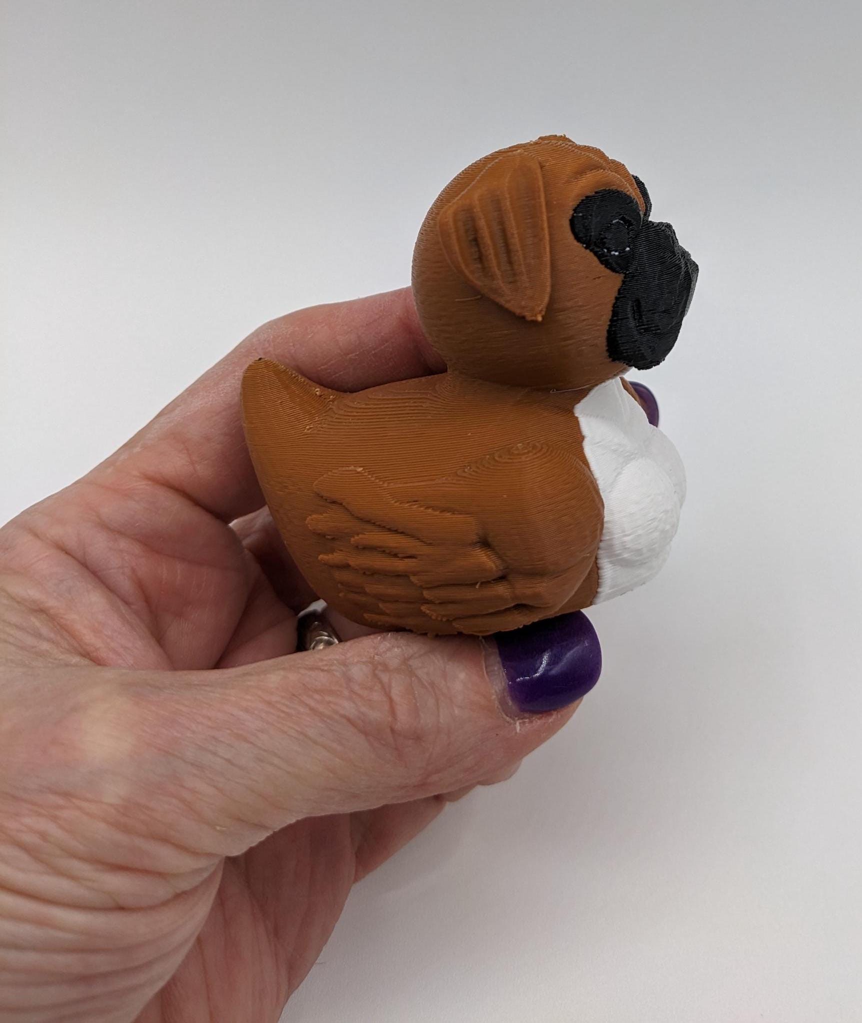Meet The Magnificent Boxer Duck, a creative and charming 3D-printed hybrid that combines the strong, playful personality of a Boxer dog with the whimsical charm of a duck! This one-of-a-kind figurine is perfect for Boxer lovers, dog enthusiasts, Jeep duck collectors, or anyone who enjoys quirky and imaginative decor. Whether displayed on a shelf, a Jeep dash, added to your collection, or given as a thoughtful gift, this Boxer Duck is guaranteed to bring smiles and brighten up any room.