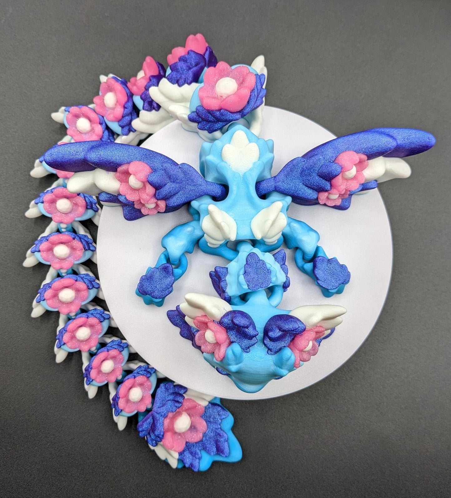 Unleash the magic of the our Beautiful Large Articulated 3D Printed Winged Kosha Axolotl Dragon! This stunning & unique creation combines the whimsical charm of an axolotl with the mythical beauty of a dragon, complete with sparkling wings & flowers.